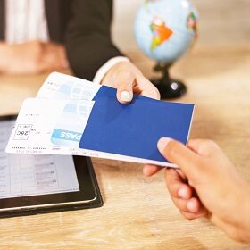 Beautiful female travel agent in glasses is giving her clients tickets and documents in the travel agency